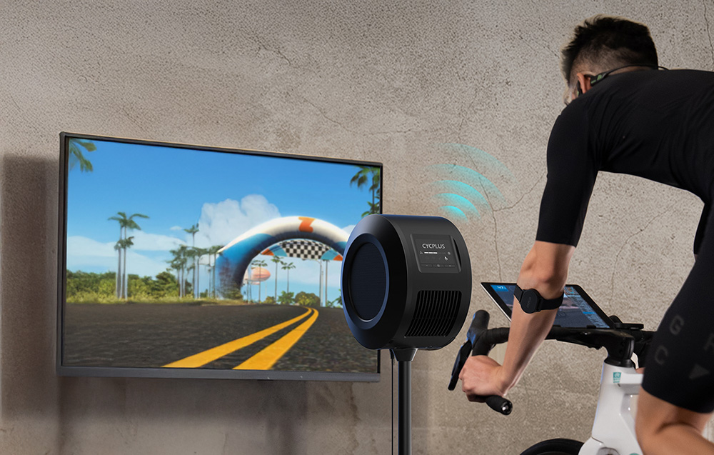 Personne sur un vélo stationnaire avec ventilateur et écran avec application d'entraînement