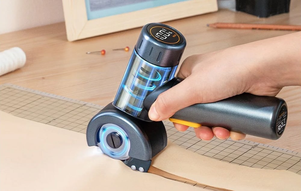 La découpeuse électrique avec affichage découpe un matériau beige.