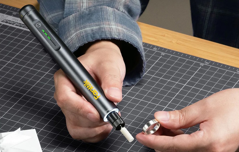 Un homme meule une bague en argent avec une meuleuse Fanttik.