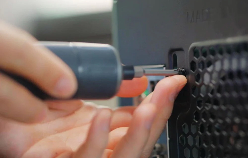 La vis vissée dans l'ordinateur avec un tournevis électrique.