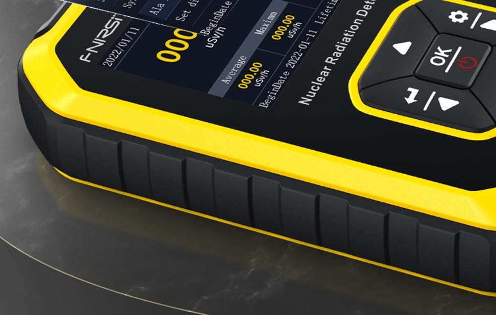 Gros plan sur le côté du boîtier jaune et noir du détecteur de radiation posé sur une surface en pierre.