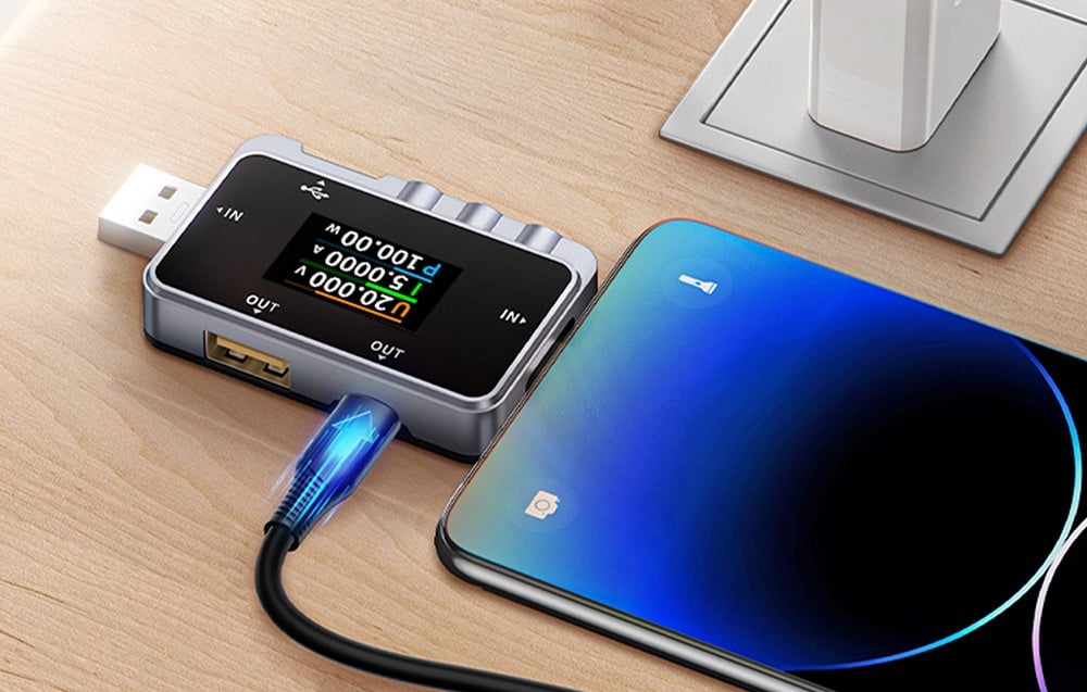 Smartphone connecté à un testeur USB sur un bureau.