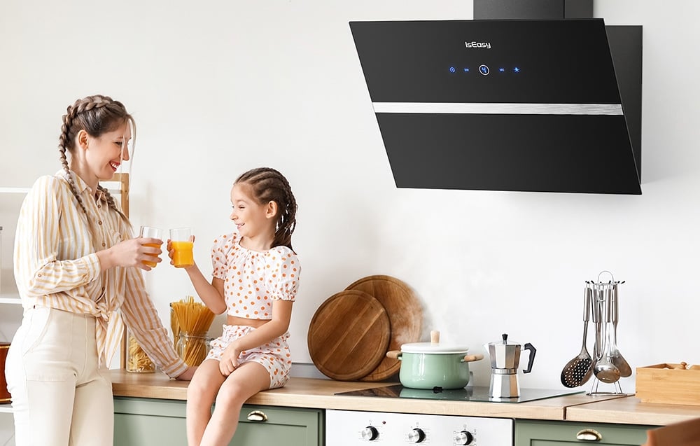 Mère et fille tenant des verres de jus d'orange dans une cuisine lumineuse avec hotte noire