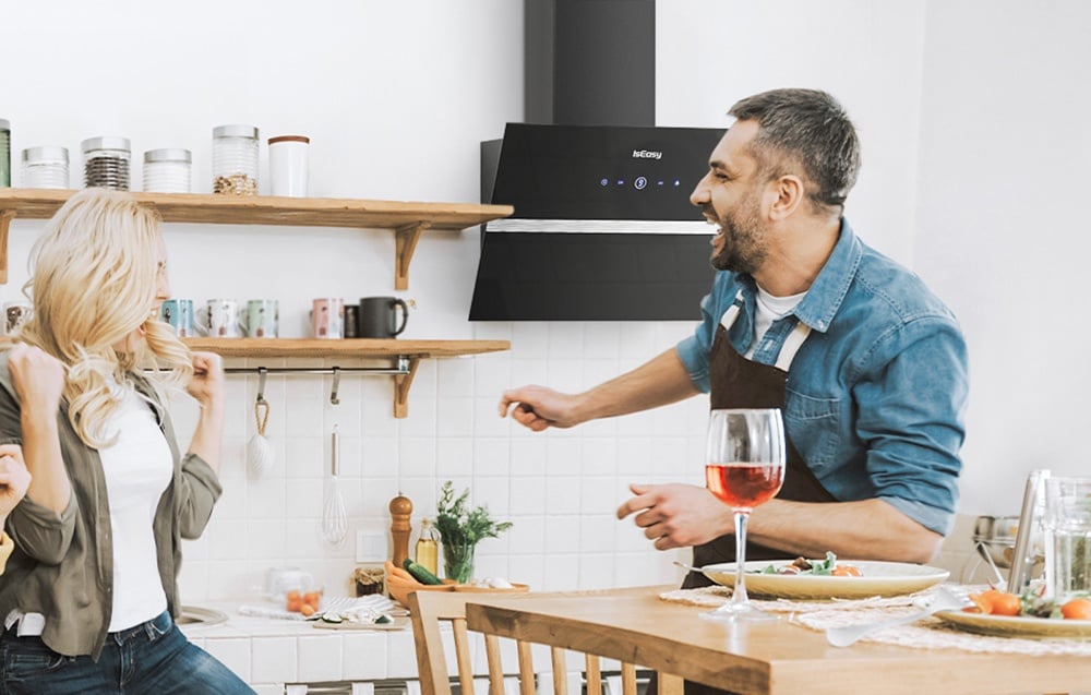 Homme et femme dans une cuisine lumineuse avec meubles en bois et hotte noire