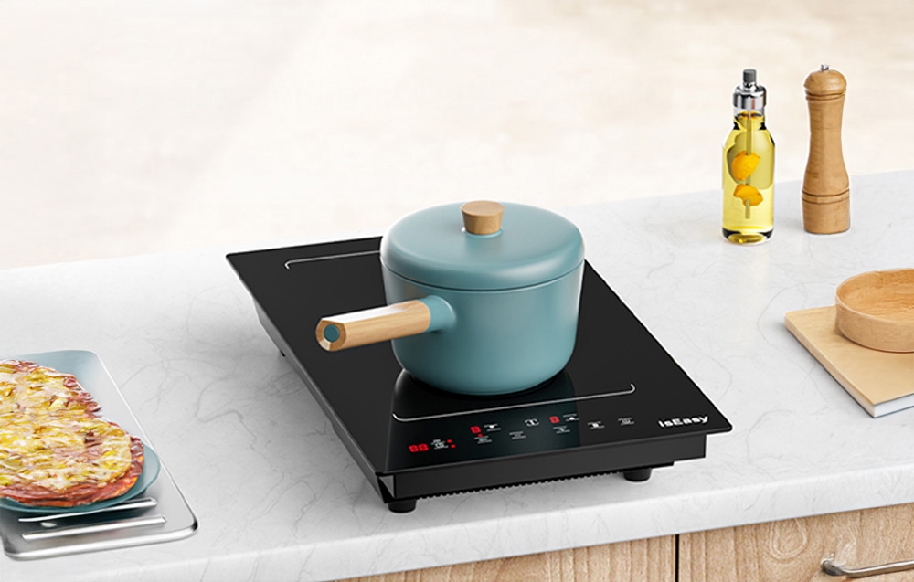 Casserole bleu-gris avec poignée en bois sur plaque à induction noire sur un plan de travail de cuisine blanc.