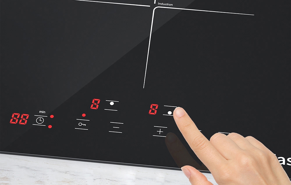 Une main touchant le panneau de contrôle d'une plaque à induction noire