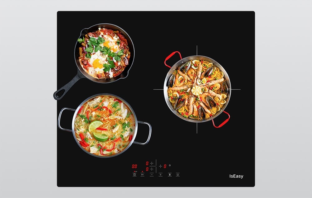 Vue de dessus de la plaque à induction avec deux casseroles et une poêle avec des plats de différentes couleurs