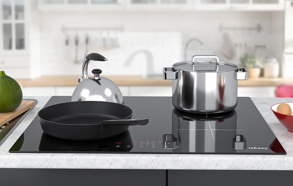 Plaque de cuisson à induction avec poêle noire, bouilloire argentée et casserole en acier inoxydable dans une cuisine lumineuse