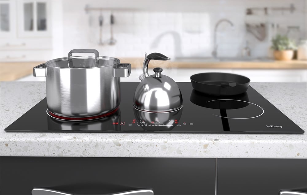 Plaque à induction avec casserole, bouilloire et poêle noire dans une cuisine lumineuse