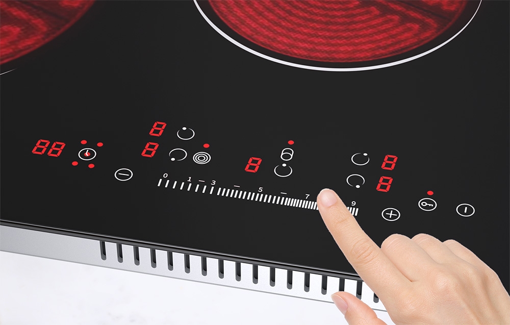 Un doigt pointe vers le panneau de contrôle de la plaque céramique avec des chiffres rouges et des symboles blancs