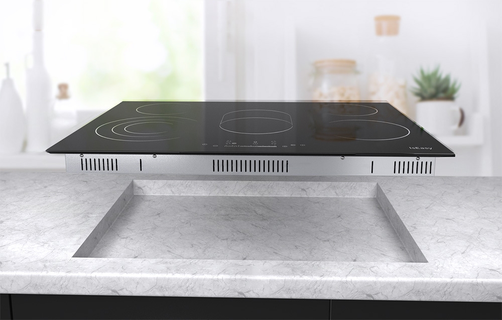 Plaque à induction avec trous de ventilation visibles au-dessus de la niche dans le plan de travail gris