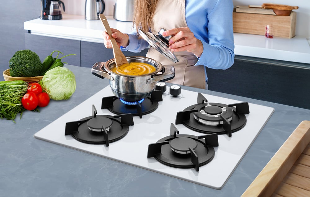 Femme remuant de la soupe dans une casserole sur la cuisinière à gaz, légumes frais à côté