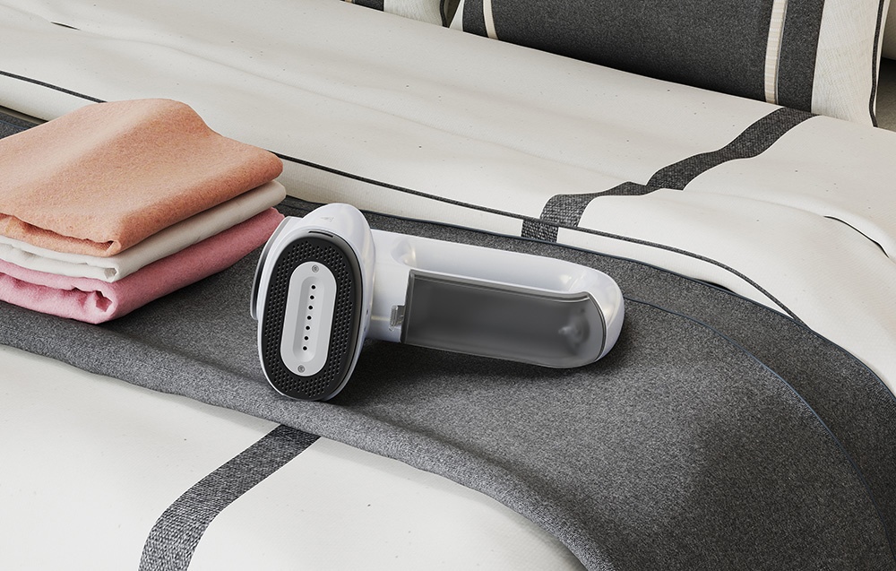 Le défroisseur blanc repose sur le lit à côté d'une pile de serviettes colorées