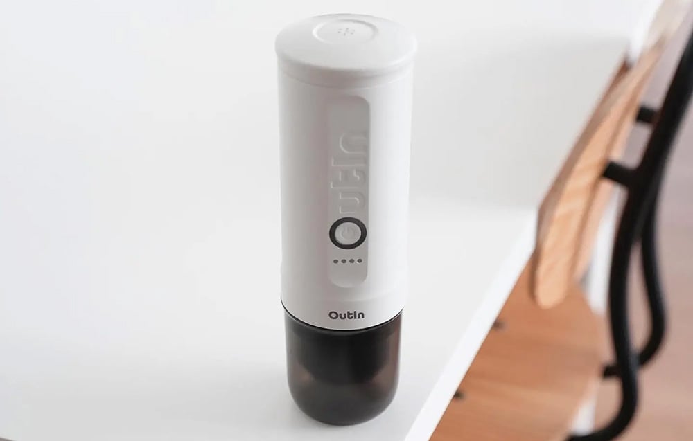 La machine à café sans fil Outin repose sur une table blanche.