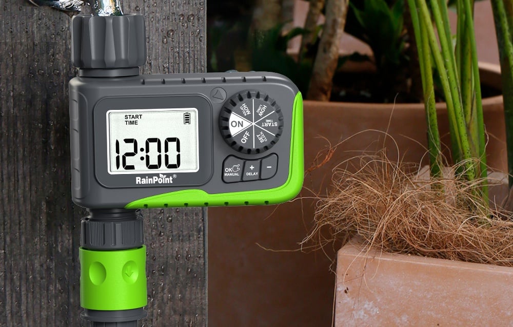 Minuteur d'arrosage sur un mur à côté d'un pot de plantes