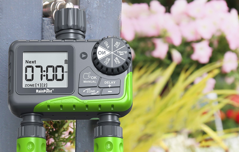 Contrôleur d'irrigation RainPoint avec deux sorties d'eau fixé à un robinet, avec des fleurs en arrière-plan