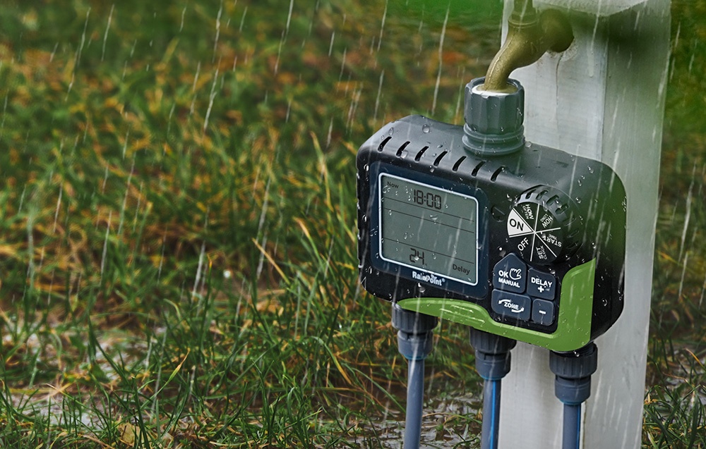 Contrôleur d'arrosage RainPoint fonctionnant sous la pluie, monté sur un poteau blanc sur la pelouse