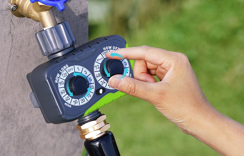 Main tournant le cadran du programmateur d'arrosage monté sur un robinet de jardin