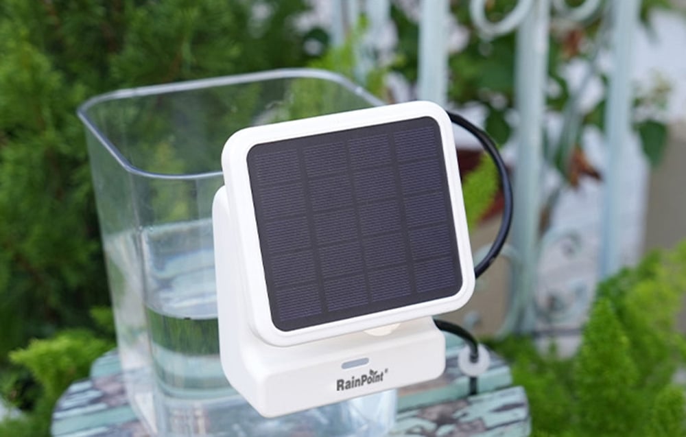 Panneau solaire RainPoint à côté d'un conteneur d'eau sur un balcon ou dans le jardin