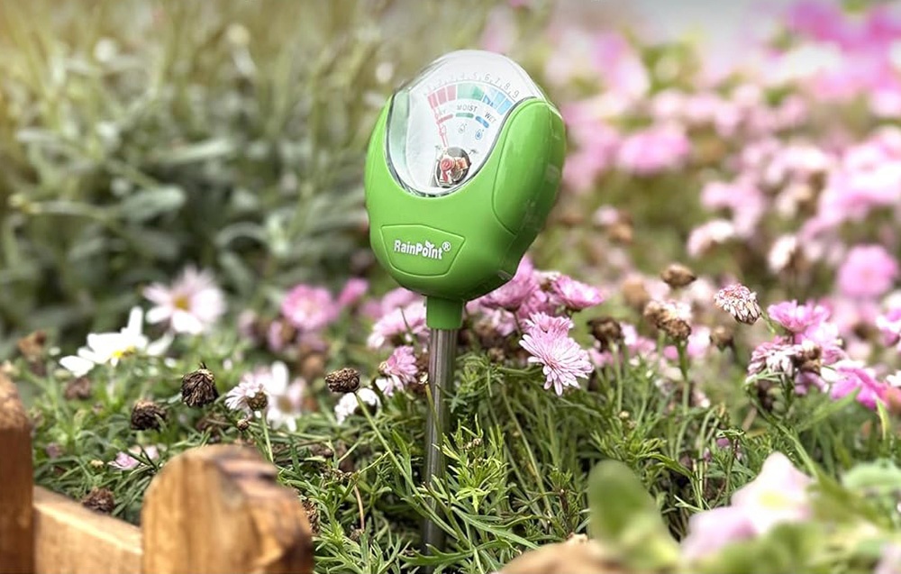Testeur d'humidité RainPoint placé parmi des fleurs de jardin roses en fleurs